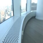 A white bench in front of a window.