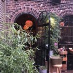 A brick building with plants growing in the corner.