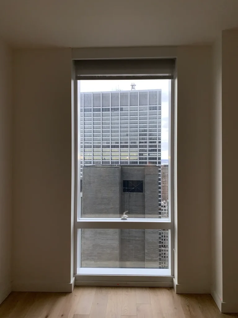 A window with blinds in the corner of an empty room.
