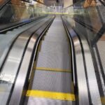 A close up of an escalator with yellow lines