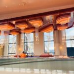 Modern indoor pool area with large windows and wooden ceiling accents.