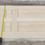 A wooden door with a tape measure on it.