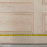 A wooden door with a yellow measuring tape on it.