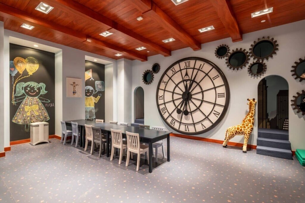 A room with a large clock and a giraffe.