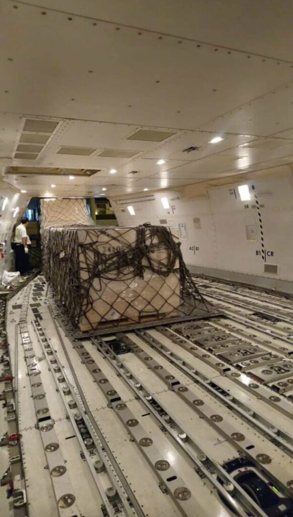 A cargo train with a cage on the side of it.