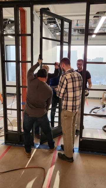 A group of people standing around in front of windows.