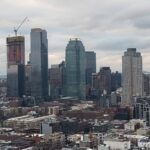 City skyline with skyscrapers under cloudy sky.