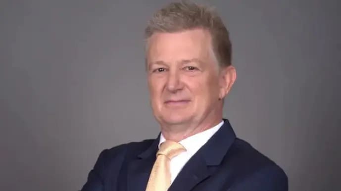 Professional man in a suit posing against a gray background.